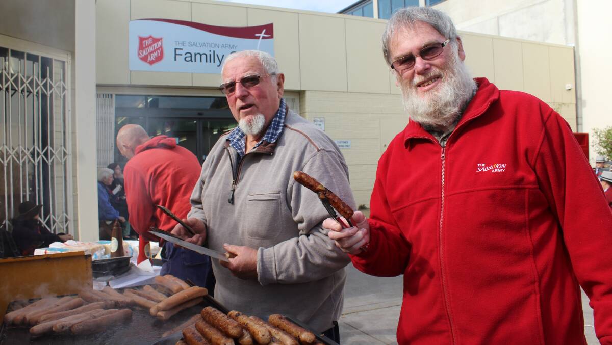 SIZZLE: Bill Handcock and Laurie McArthur cook up a story outside the Bega Salvation Army store on Saturday to help launch the Red Shield Appeal. 