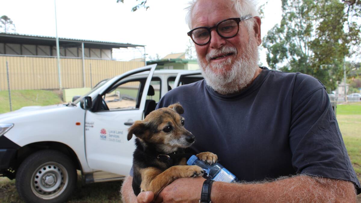 Peter Burgess holds a shaken but safe Milly after she was brought to the Bega Showgrounds by Local Land Services after two days alone in Tathra.