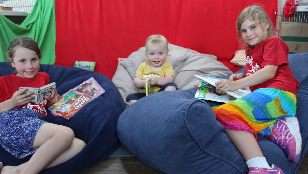 YOUNG FUN: Jane, Caleb and Grace Chapman from Western Sydney settle in to read their free books from the Bega Rotary book fair in the kid's corner on Friday.