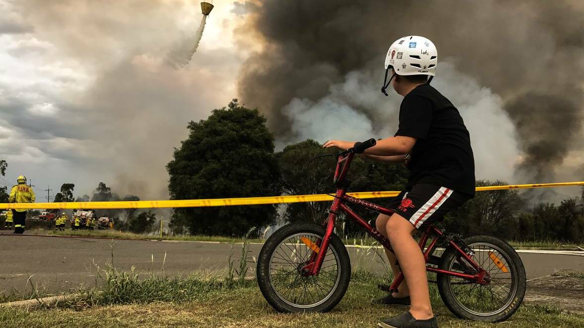  Luke Dietrich, 11, from nearby Appleton Road, watches from relative safety as plumes of smoke rise from the deliberately-lit bushfire near Kurri Kurri. Pictures: Marina Neil.