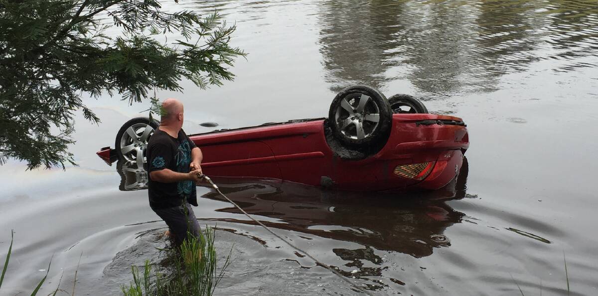 LUCKY ESCAPE: The driver escaped as the car plunged into the Yowaka River. Shane Goddard, of Pambula NRMA about to connect the tow winch.