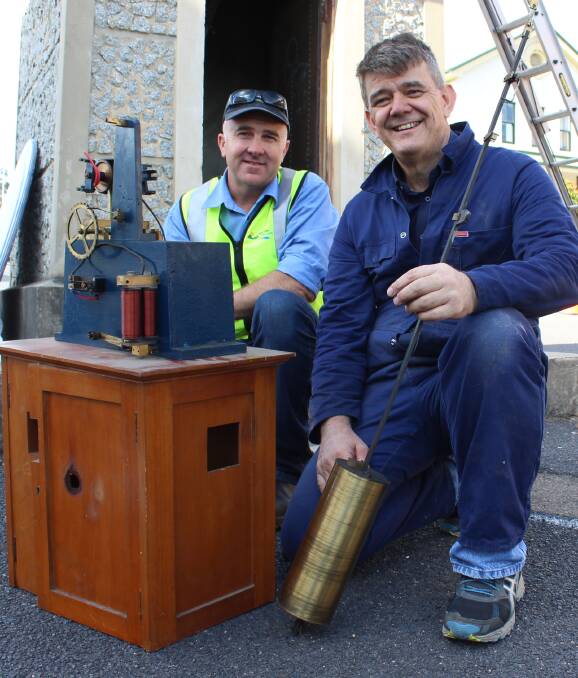 END OF AN ERA: Cliff Shipton and Andrew Markerink show off the Bega clock tower's old interior mechanism and the pendulum, which is estimated to weigh about 15kg. 