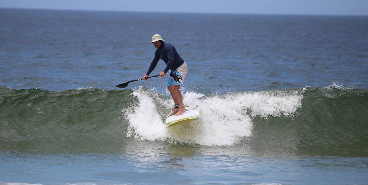 Balance: A stand up paddle boarder cruises over the lip of a wave on Sunday morning with more than 200 surfers hitting the water for the Merimbula Classic.  