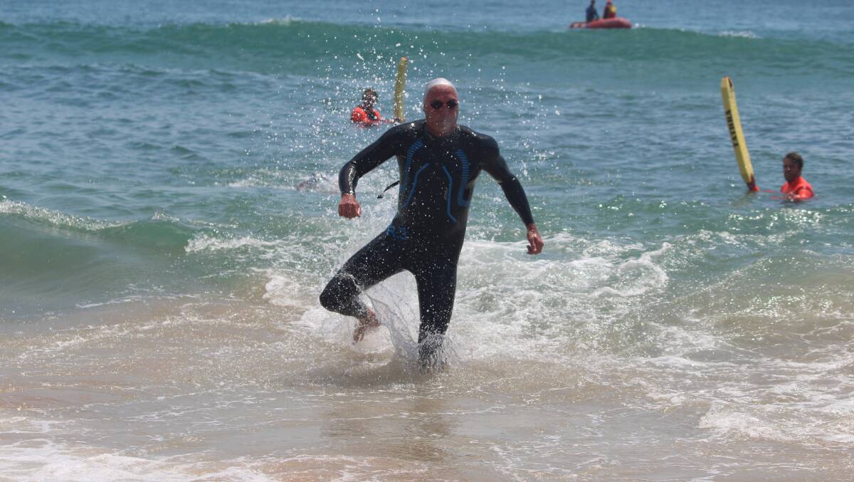 Rivalry: John Fox emerges from the water just seconds behind Splash for Cash winner James Macri at Tathra Beach on Sunday.
