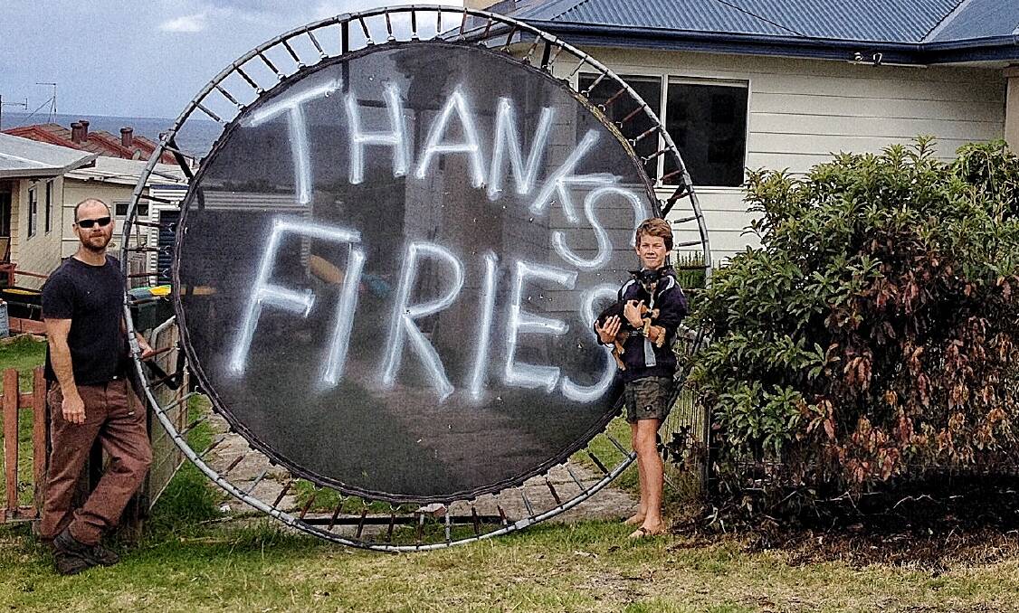 Luke Hamilton and son Otis Waratah with their message to everyone who helped save their Tathra home on Sunday. Photo: Supplied