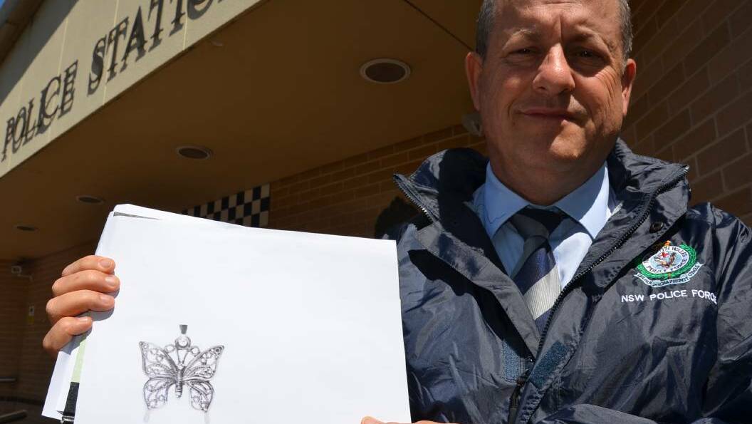 Detective Inspector Kevin McNeil with a copy of the butterfly pendant.