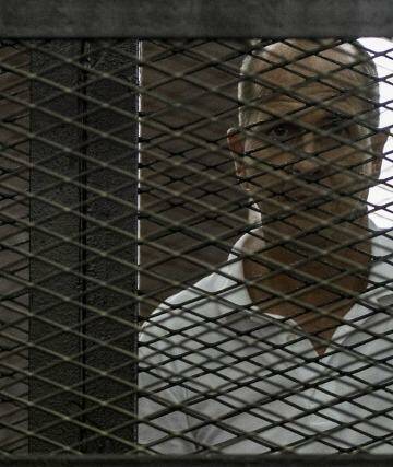Jailed Australian journalist Peter Greste pictured inside the defendants cage during his trial. Photo: Khaled Desouki/AFP