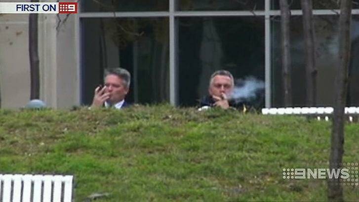 Finance Minister Mathias Cormann and Treasurer Joe Hockey enjoy cigars outside The Treasury in Canberra during budget preparations. Photo: Nine News
