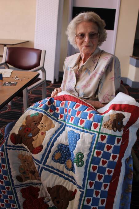 Thelma Cave shows off a quilt that is one of the sewing group’s projects.