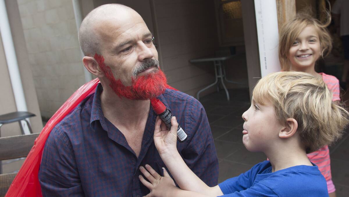 Riely Lingard, 6, colours Darrin Blanch's beard  to raise funds for charity  while Yasmin Lingard, 8, looks on.
