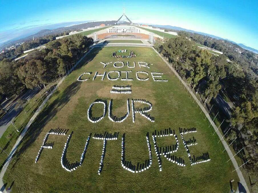 Participants at the Australian Youth Climate Coalition National Summit made a sign on the lawns of Parliament House. 