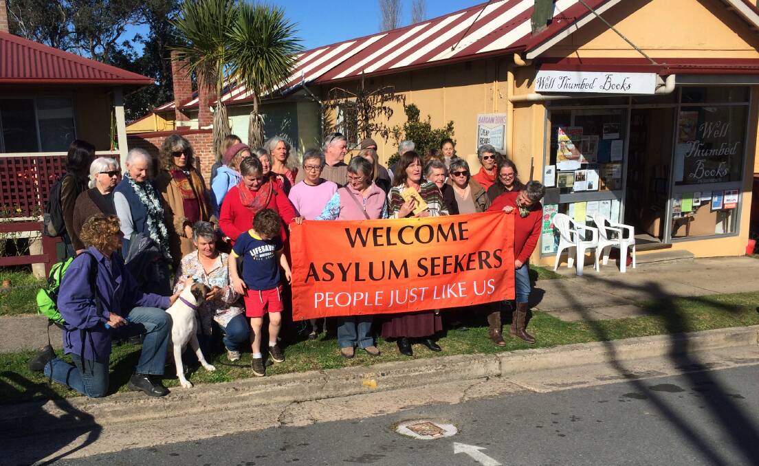 Those celebrating the launch of Isobel Blackthorn’s novel “Asylum” in Cobargo last Saturday hold a banner welcoming asylum seekers. 