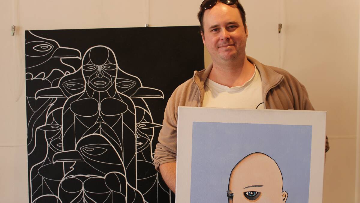 Young Merimbula artist Max Hannan prepares to hang his work at Spiral Gallery this week.