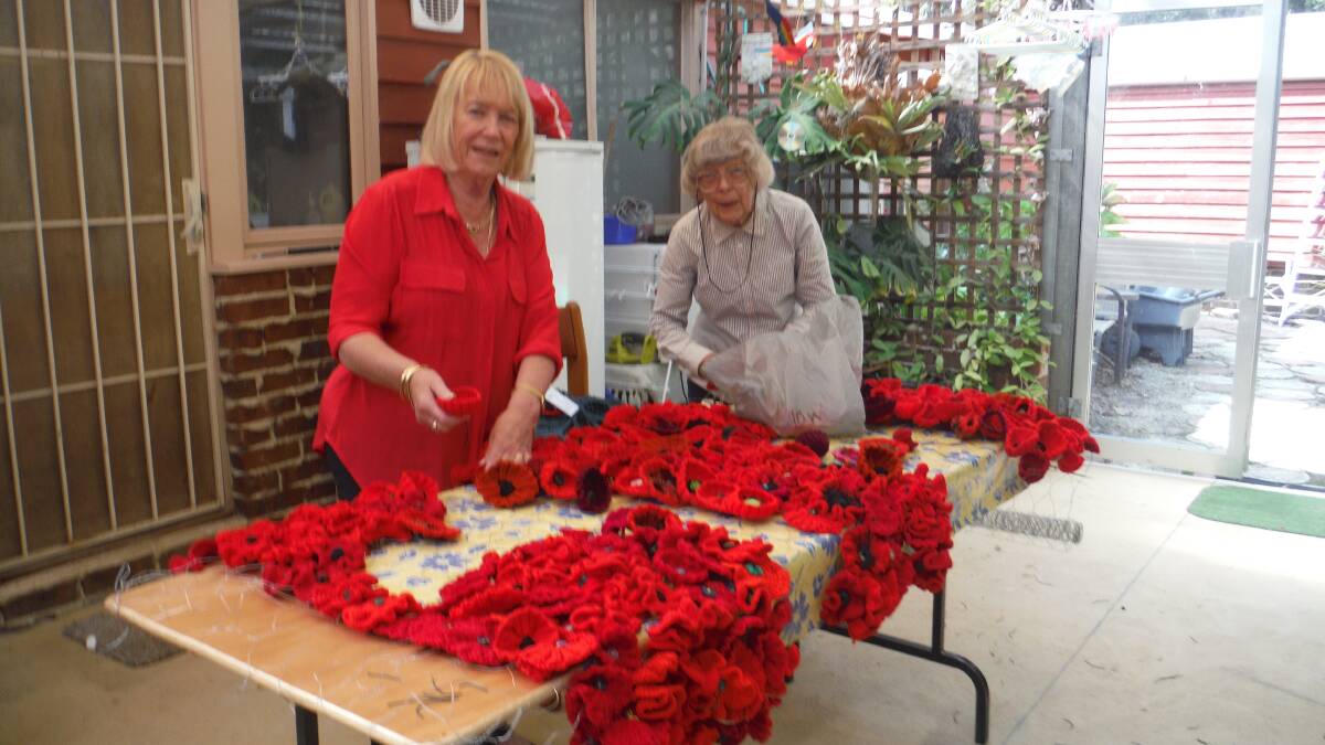 United Hospital Auxiliaries Tathra branch president Bev Slater and life member Barbara Law assemble the poppy carpet. 