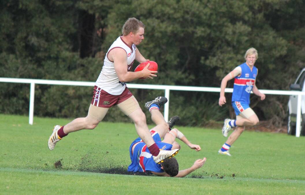 • Jason Ainsworth takes a running mark, while his Merimbula opponent takes a  tumble on Saturday.