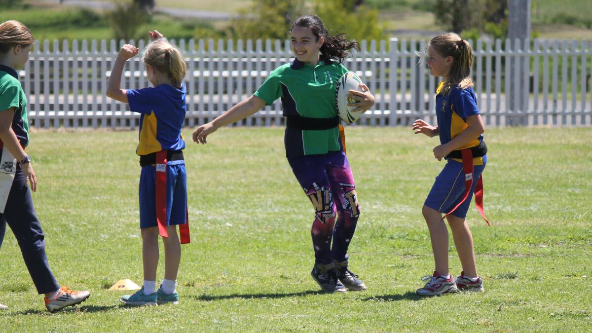 • It is all smiles as Bega Valley Public School’s Nikita Brown (centre) is tagged by players from St Pats at a rugby league gala day on Wednesday. 