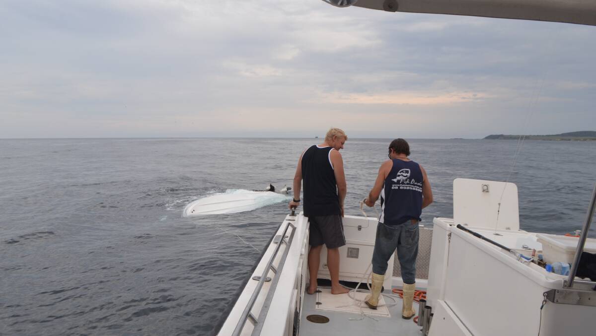 SALVAGE MISSION: Nitro skipper Benn Boulton and Andrew Cowley work to secure the upturned vessel. Photo by Stan Gorton  