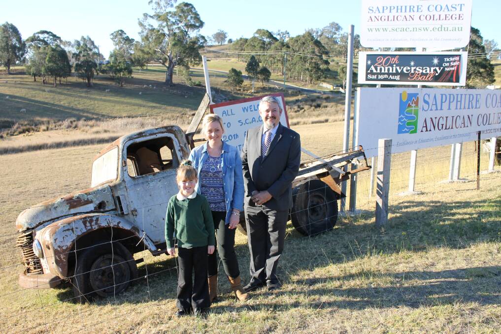 Kirsty Umbers with her daughter Bridie and Sapphire Coast Anglican College principal Andrew Duchesne next to one of the old utes brought out for the upcoming country fair. 