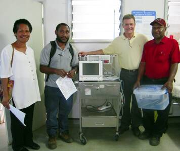 • July, deputy matron of Mt Hagen hospital, pictured with Dr Duncan MacKinnon flanked by two junior doctors from the accident and emergency department, who were being shown how to use monitoring equipment donated by Bega. July is described as a lovely lady who cried when the Australians returned when they said they would.
