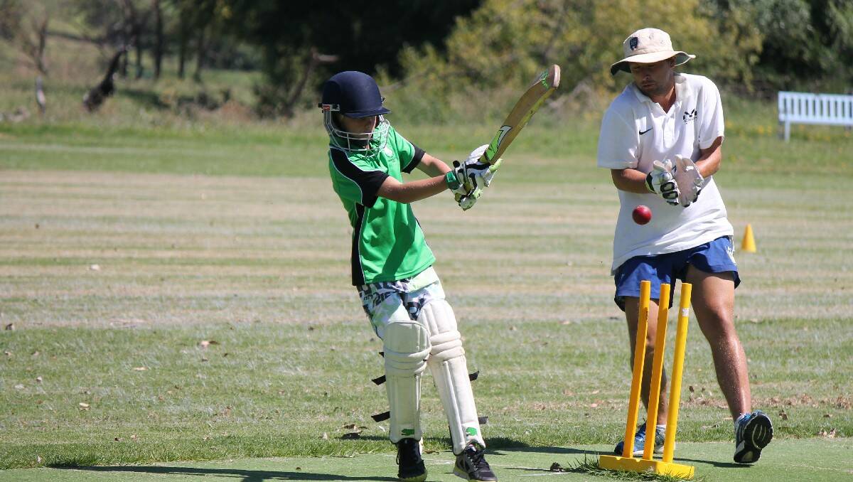 ACT Comet Vele Dukoski attempts to a glove a ball, smashed by a Bega Valley junior cricketer.