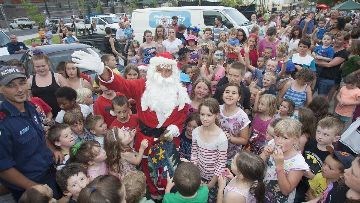 Santa is mobbed upon his arrival at the Christmas carols event in Littleton Gardens, Bega.