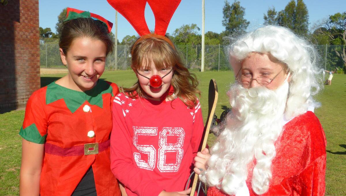 Megan “Elf “ Rutherford, Lexie “Rudolph” Odd and Zoe Holsworth as Santa enjoy themselves at the Bermagui Christmas carols. Photos: Judy Wells.