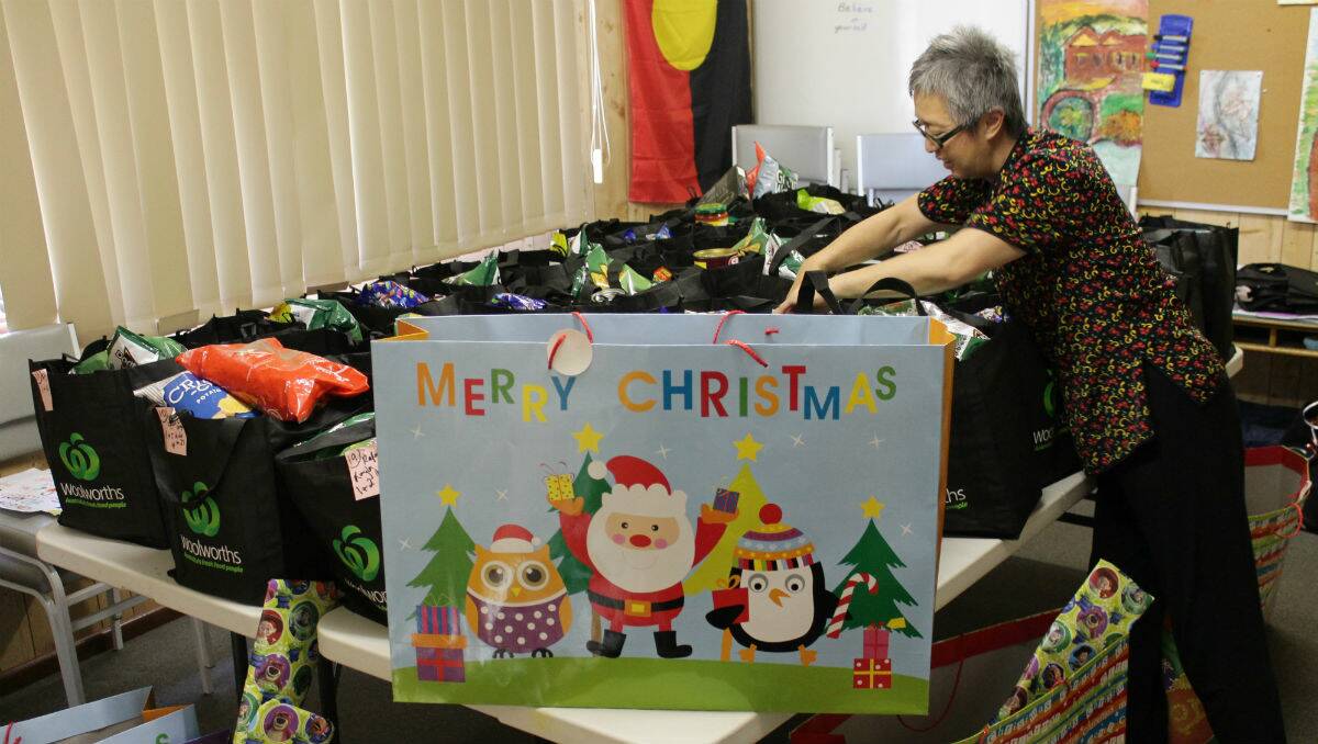Linda Sang helps pack Christmas hampers full of food and presents the Women's Resource Centre is distributing to Bega Valley families in need.