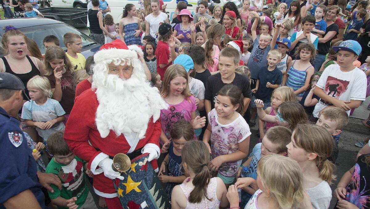 Santa is mobbed upon his arrival at the Christmas carols event in Littleton Gardens, Bega.