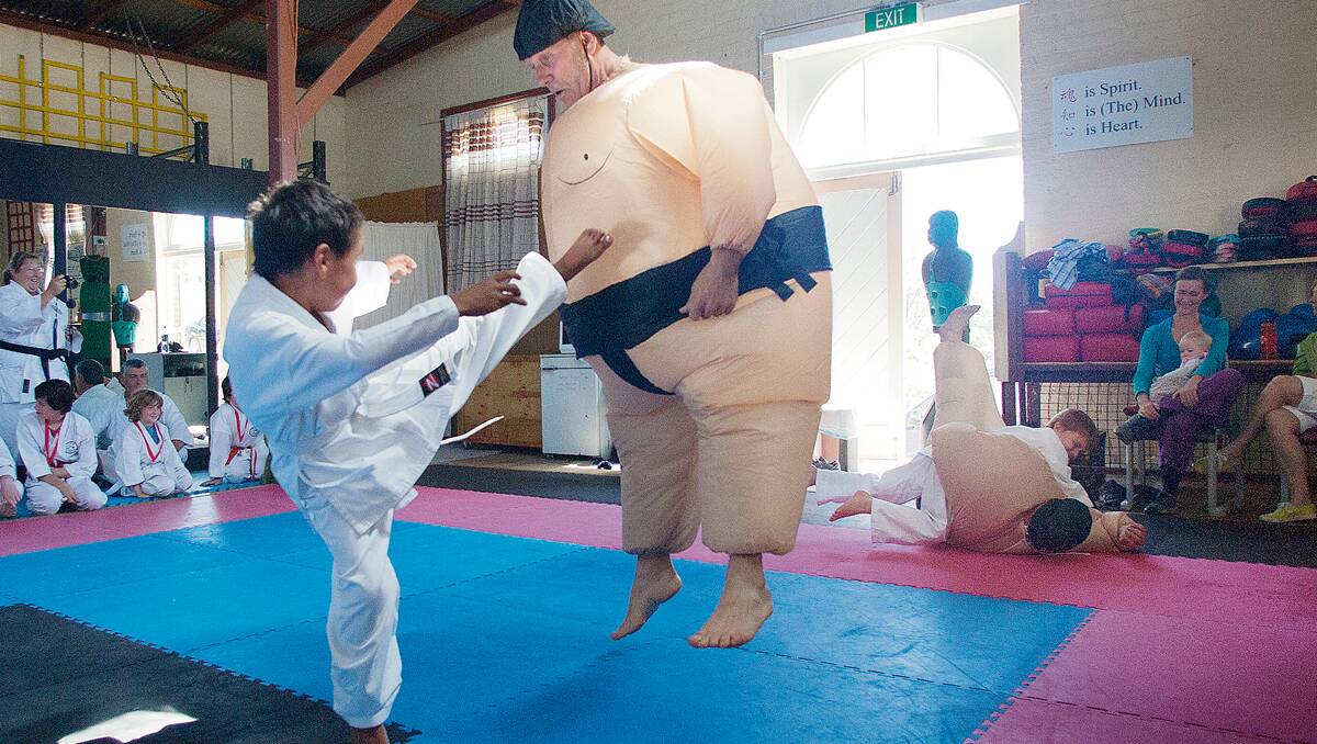 • Karl Maher (left) sends sumo wrestler Andy Zarins, aka Mr Sookie La La, flying with a high kick during the Candelo dojo’s presentation day recently. Photos: Peter Smith