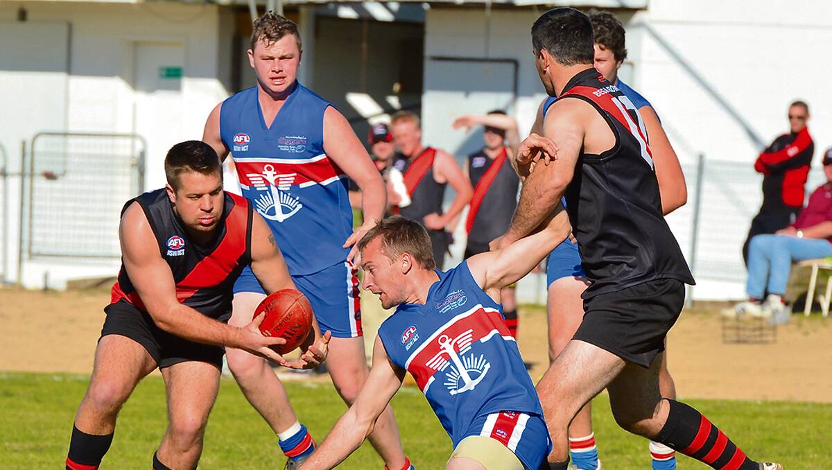 • Bega Bomber Jason Heffernan clears the ball from two Merimbula Diggers during a match last year.
