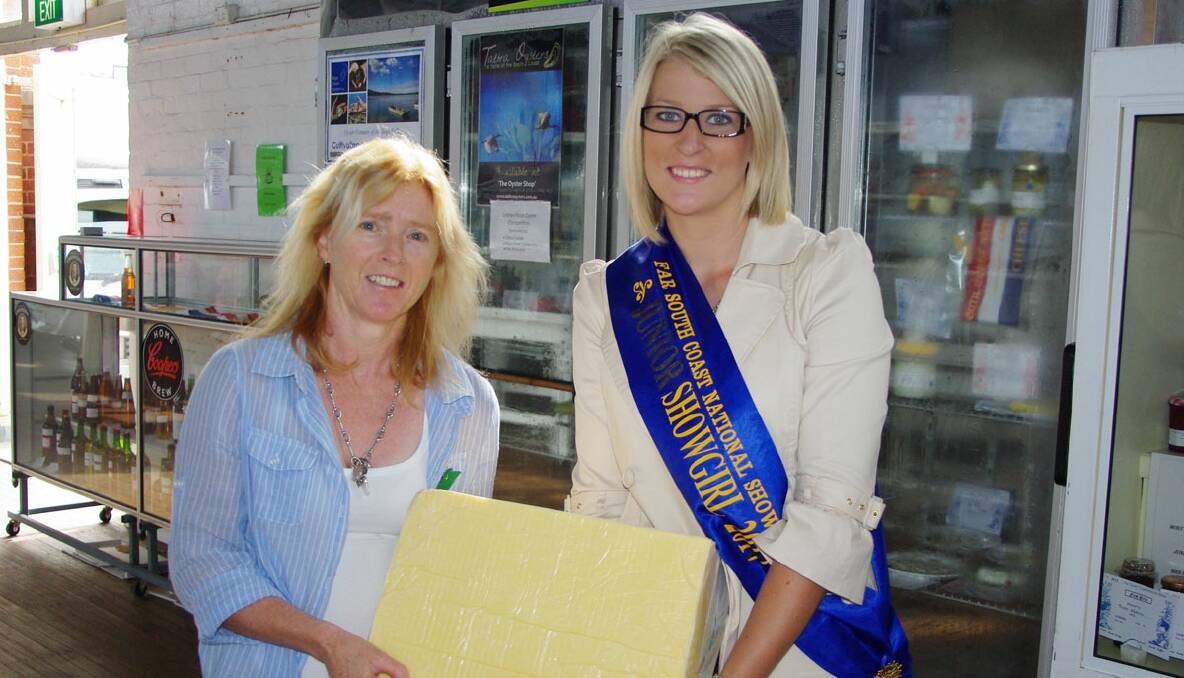 Barbara Rogers and 2012 Miss Showgirl Ali Preo lift the 20kg block of cheese they had to run with in last year’s Great Bega Cheese Race. 