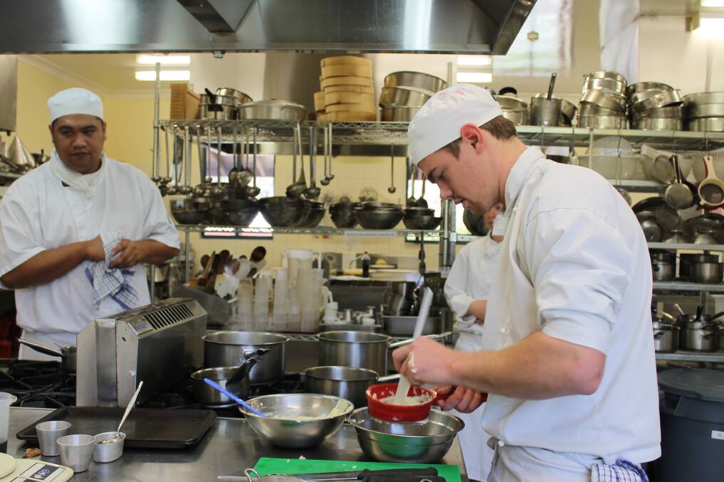 Noo Ben watches as teammate Jackson Griffin prepares his dessert in the Bega TAFE Tourism and Hospitality kitchen.  