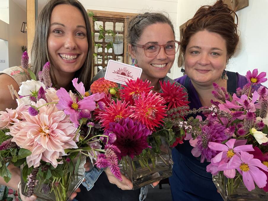 Smiles all round at Bega Chamber of Commerce's International Women's Day lunch. Left to right - Caitlin McDowell, Tara Chiu and Krystina Kasprzak holding up beautiful flower arrangements by local florist Darcie Nicol. Picture by Amandine Ahrens