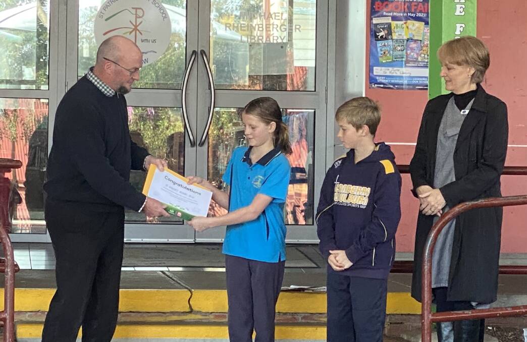 Bega Woolworths store manager Craig Ferris presents confirmation of their successful grant application to St Patrick's Primary School captains Madison and Lincoln alongside principal Jo Scott-Pegum. Photo supplied