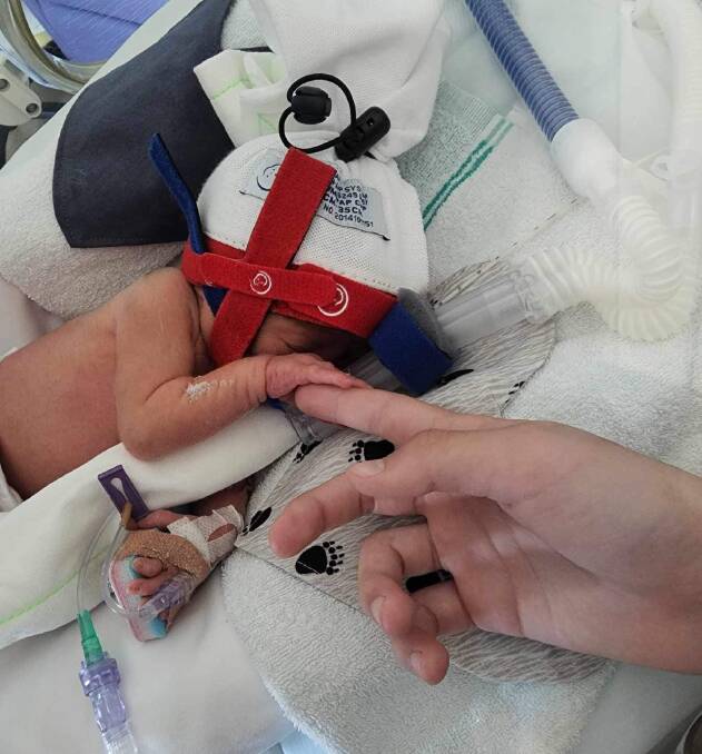 Ochre Jessop holds his mother's hand after being born prematurely at 30 weeks at the Centenary Hospital for Women and Children in Canberra. Picture supplied. 