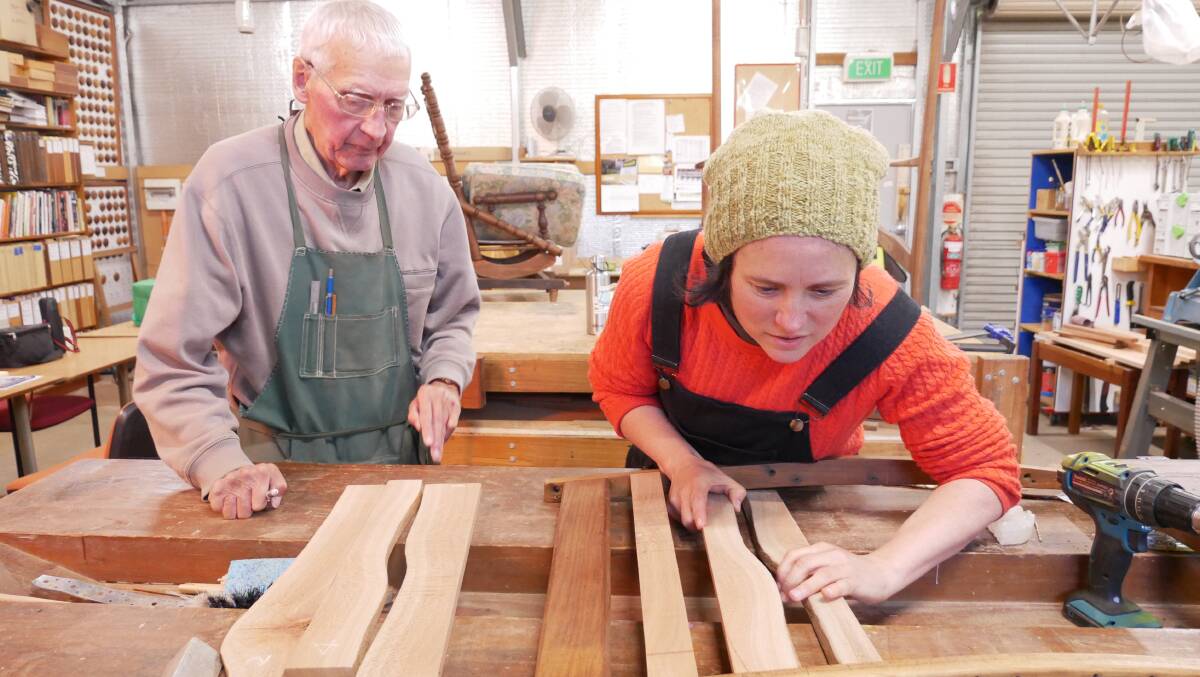Woodies President Bruce Dunlevie and member Sarah Davis work on a chair Ms Davis was restoring from her home that was originally very uncomfortable. Photo: Ellouise Bailey