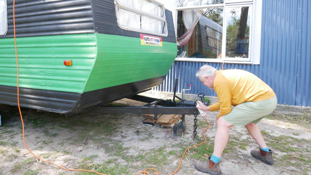 Geof Maher applying black spray paint to the towbar of the caravan. Picture: Ellousie Bailey
