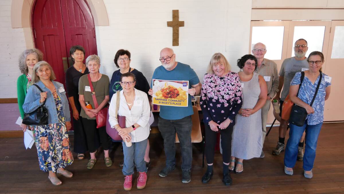 Christine Welsh stands next to her husband Peter Buggy (holding the sign) with a group of potential volunteers who attended a meeting on March 14 to discuss the relaunch of Ricky's Kitchen by Sapphire Community Projects. Photo: Ellouise Bailey 