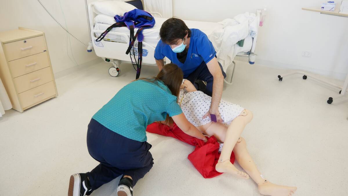 Two students practise assisting an elderly patient from the floor and back into bed. Photo: Ellouise Bailey