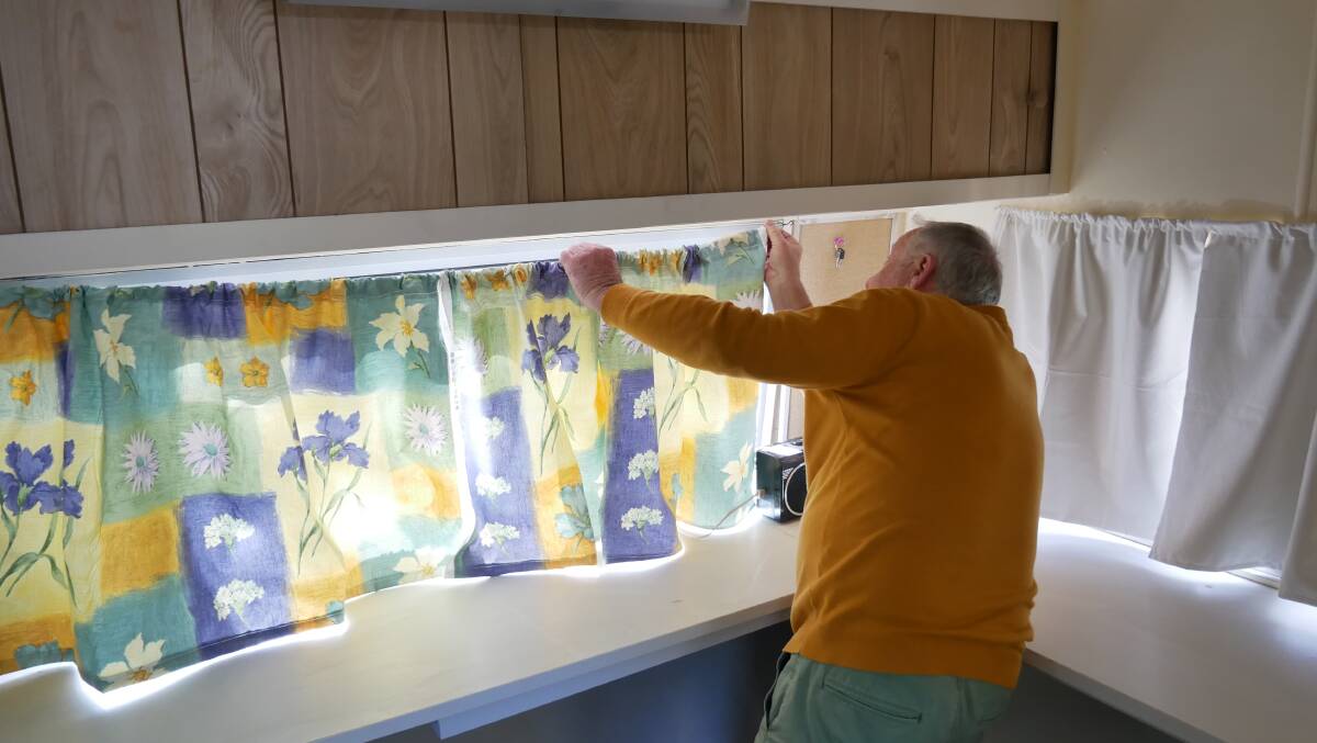 Geof Maher installing a curtain in the caravan he is currently working on. Picture: Ellouise Bailey