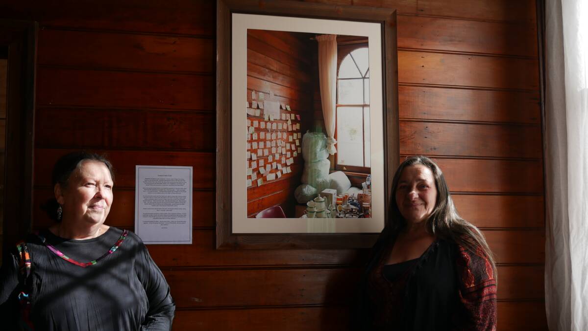 Quaama Progress Association president Glennda Heino and secretary Veronica Abbott stand next to the photograph commemorating the Quaama Hall and how it was used during the Black Summer bushfires. Photo: Ellouise Bailey