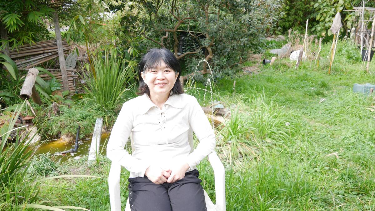 Reiko Okamoto Healy in her backyard which is a small oasis of greenery. Their perimeter fence is a collection of various species of bamboo which they planted when they first moved to Bega. Behind Reiko is a small water feature which makes the garden feel tranquil and peaceful despite being located in town. 