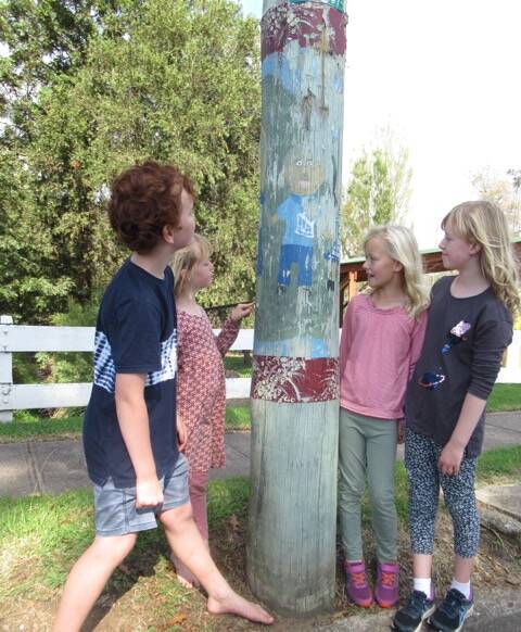 A group of children from Cobargo standing next one of the poles which will be repainted during the project. Photo: supplied