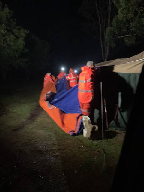 SES workers battle heavy rain on March 22 to help the James family set up a tarp over their caravan and camping trailer to prepare for the oncoming floods. 
