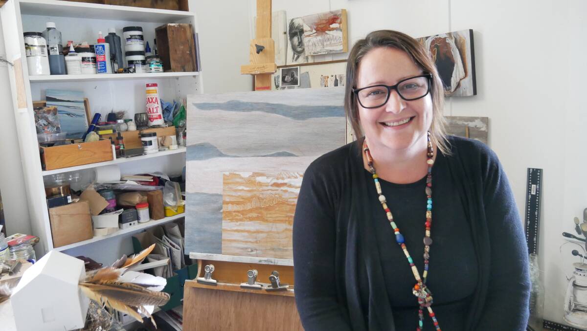 Verona Artist Karyn Thompson sitting in her home studio. Behind her is an easel with two paintings she is working on and on the walls behind her are previous paintings. Picture: Ellouise Bailey