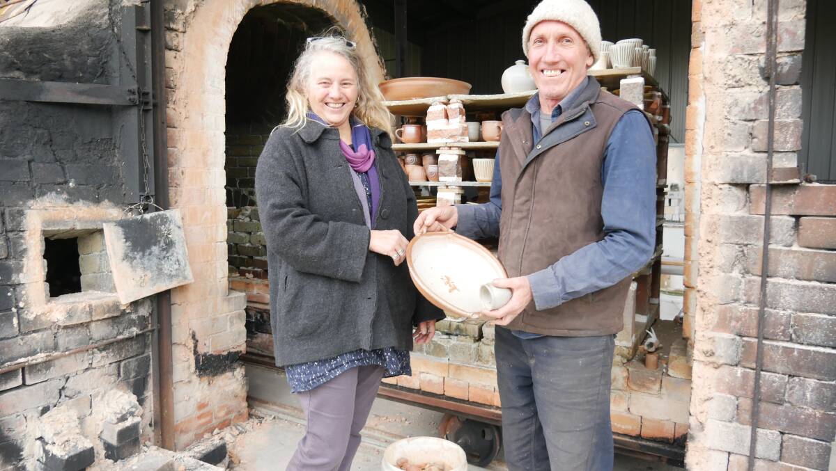 Mr Lafferty uses a wood-fire trolly kiln and Ms Powell uses an electric kiln for her work. Here they hold up a piece of Mr Lafferty's stoneware from a recent wood-firing. 
