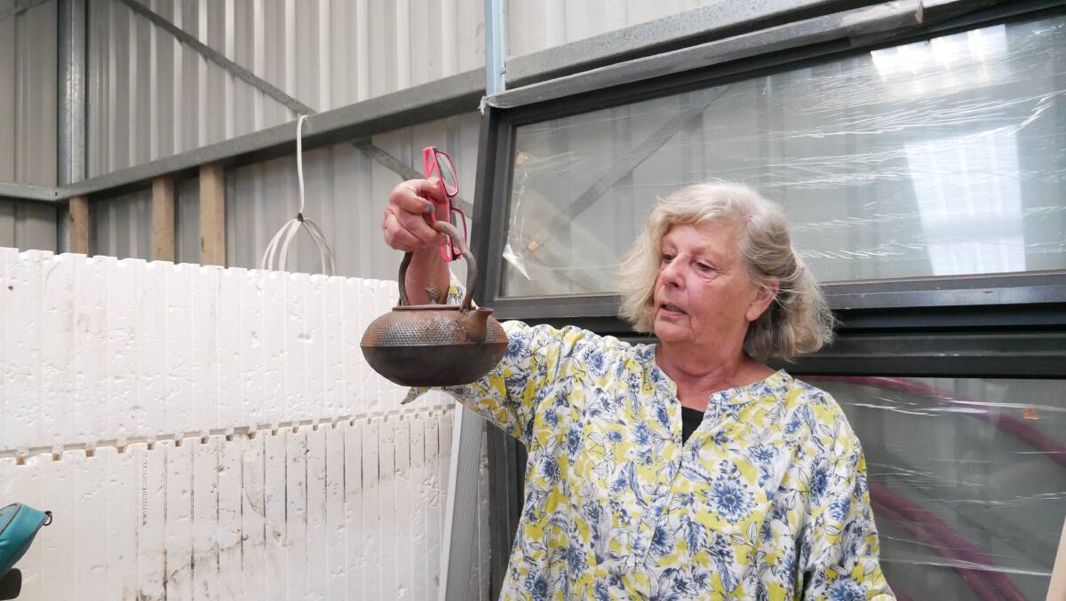 Ms Van Doorn holds up a teapot from a box of what survived the bushfires. Most of which includes cast iron pots. It also includes a laden spoon set her father gifted her mother after they married. They were the only items left after the fires. 