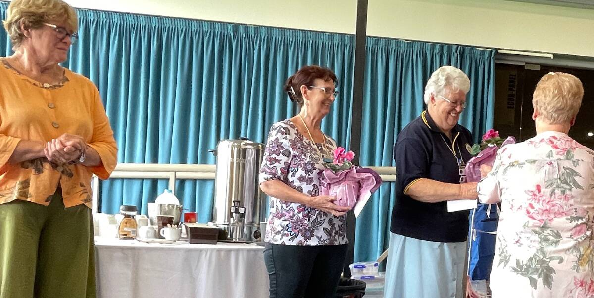 FSCG president Stephanie Stanhope watches on as FSCG Land Cookery Officer Liz Tough presents guest judges Carole Windley from Sussex Inlet and Leona Irvine from Gungahlin with cyclamens at the FSCG Land Cookery Competition. Picture by Marion Williams