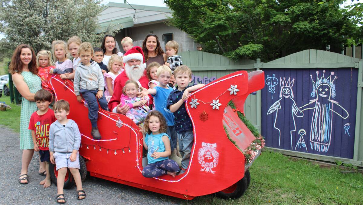 Dave Rugendyke, invites the children and staff of Cobargo Preschool to sit on the sleigh he built from a '60s golf cart in 2018, which later burnt down in the Black Summer Bush Fires two years later. Photo on file. 