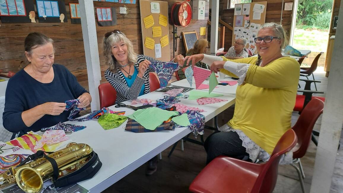 Organiser Ruth Haggar (middle) with Christine Tilsley (left) and Erin Evans (right) make flags of hope at Quaama Hall for those still displaced from the Lismore floods. Picture supplied 